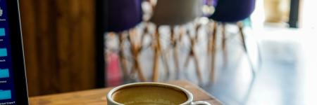 Outdoor terrace with laptop, coffee, and Brussels streetscape.